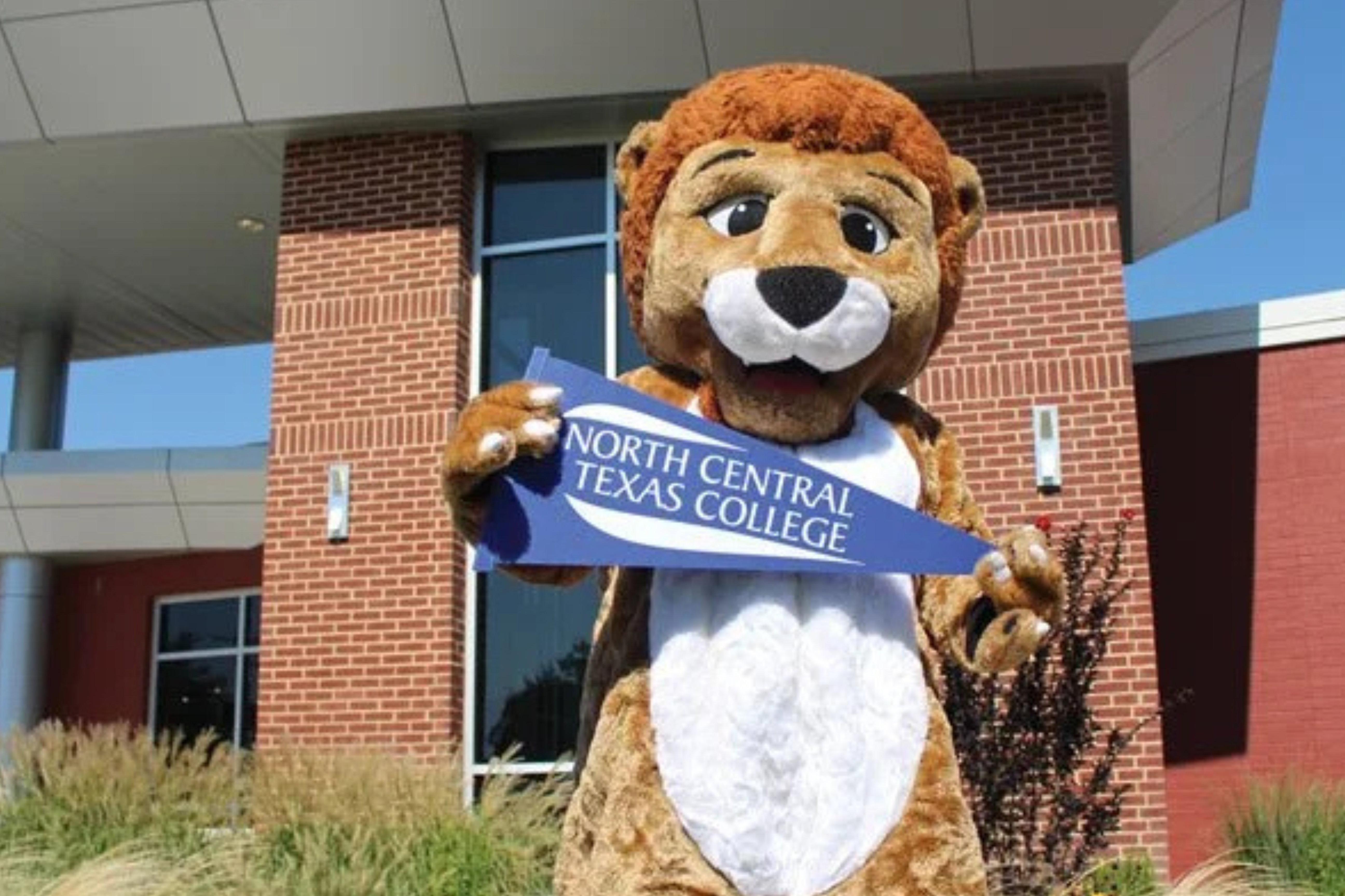 Leo the Lion mascot holding an NCTC pennant flag