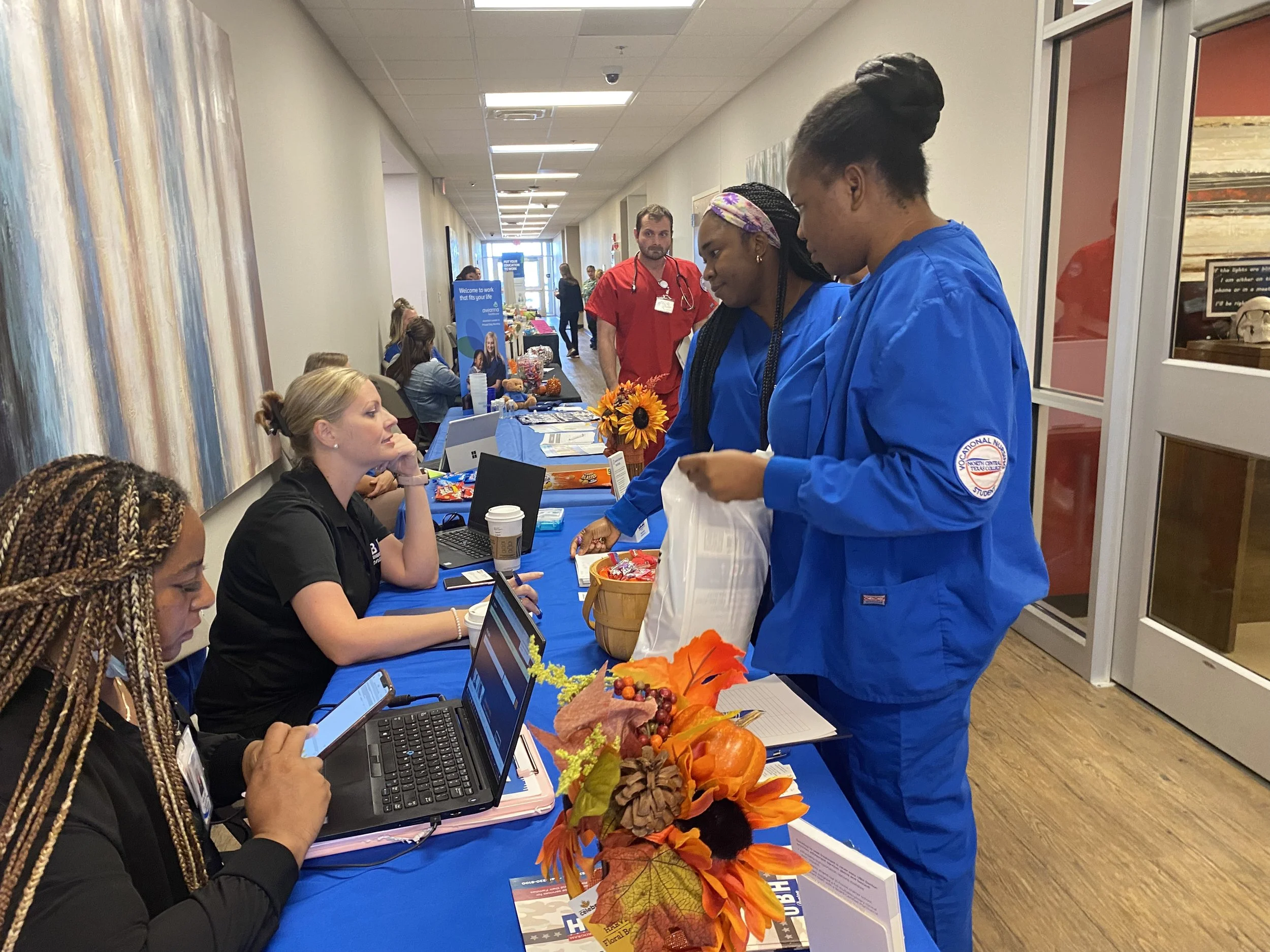Students connect with recruiters at a healthcare career fair, sharing smiles, questions, and opportunities in a busy hospital hallway.